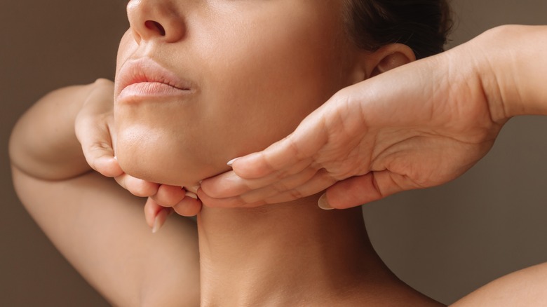 Woman stretching jawline with hands