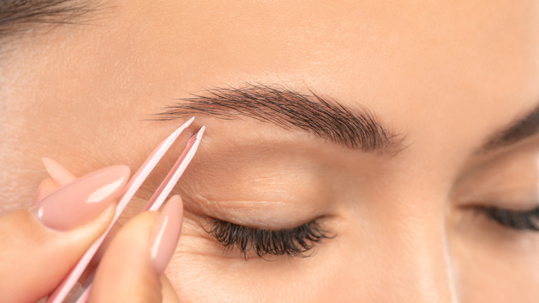 Woman tweezing eyebrows