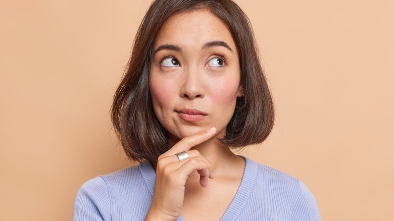 Woman thinking with hand on chin