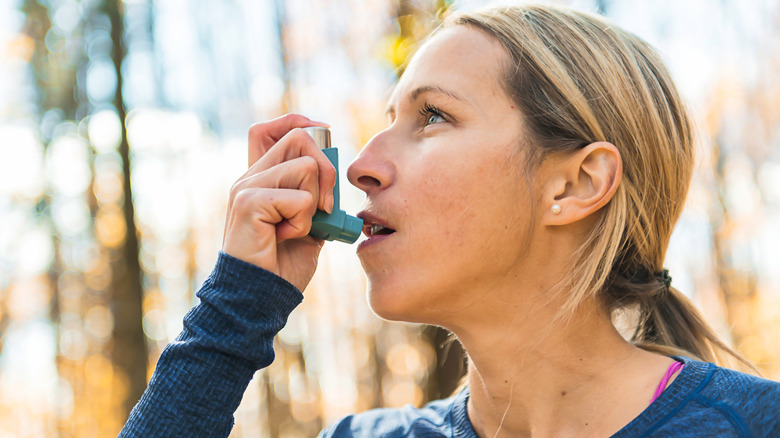 woman using asthma inhaler outside
