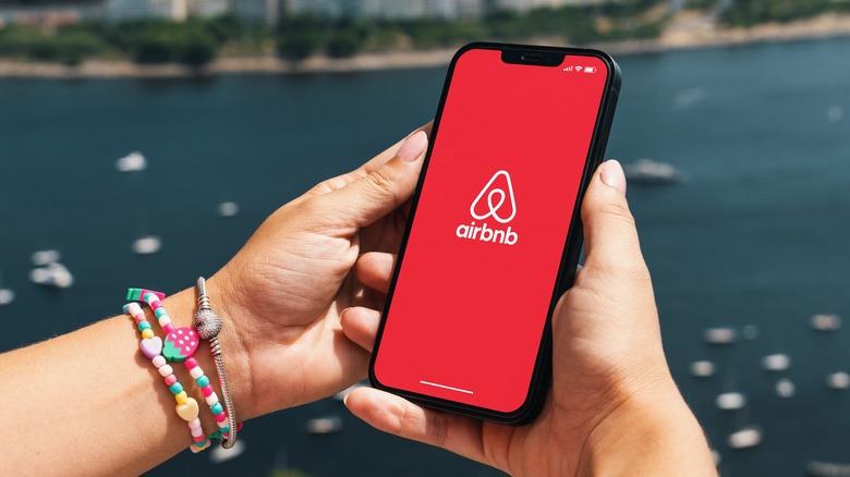 Woman holding her phone with Airbnb app over pond