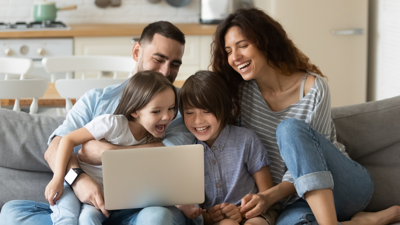 Young family sitting together on couch with laptop
