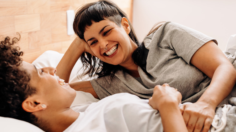 lesbian couple laughing in bed