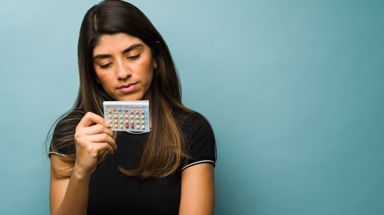 Woman looking at birth control pills
