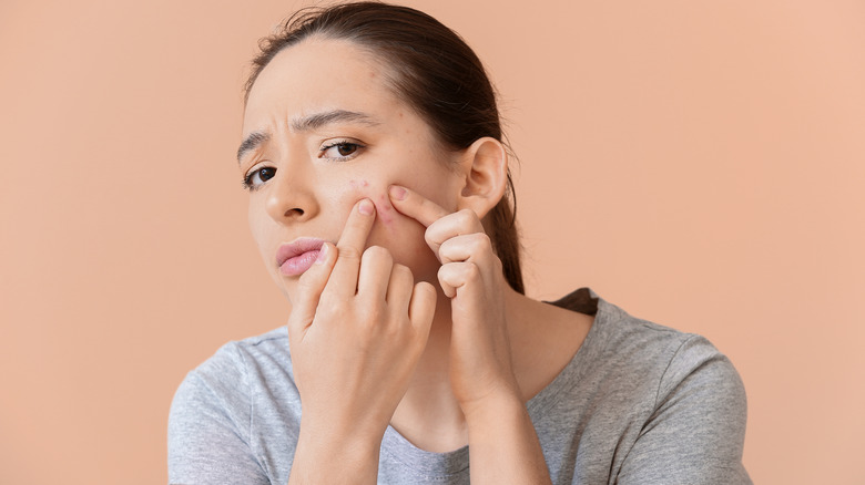 woman picking at pimples