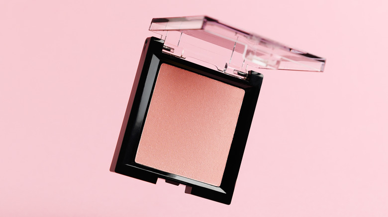Open blush compact on pink background
