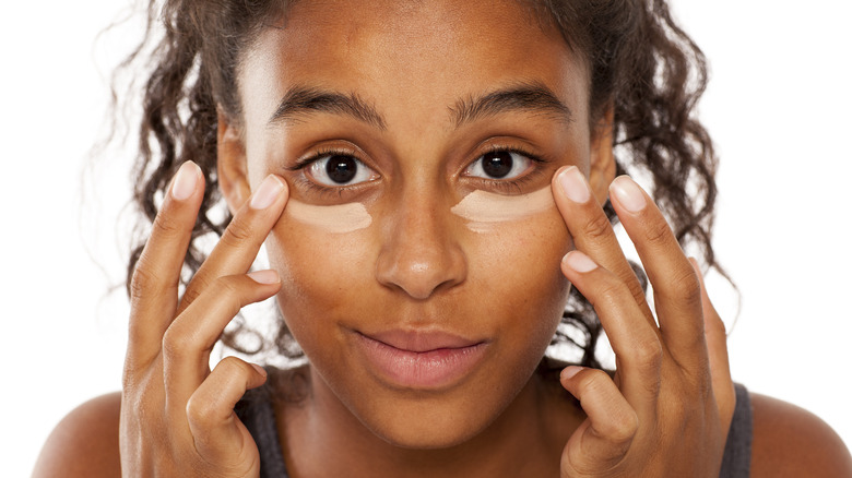 woman applying concealer under eyes