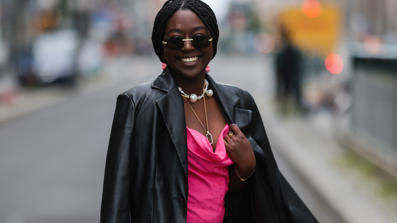 Woman with leather blazer over pink slip dress.