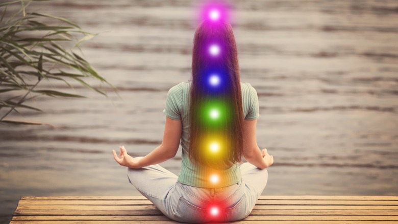 woman meditating with lit chakras