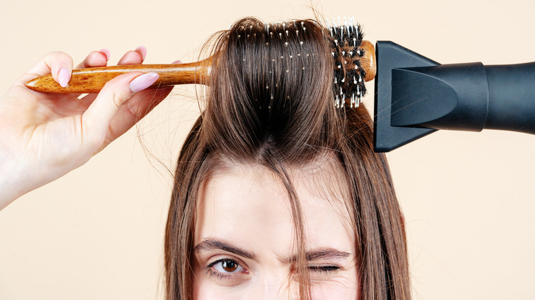 woman blowdrying hair with round brush