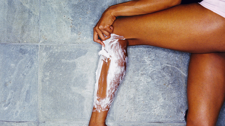 woman shaving her legs 