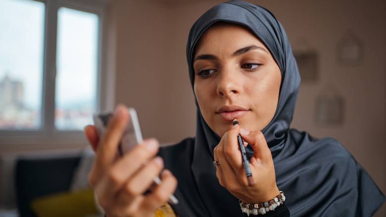 hijabi applying lip liner