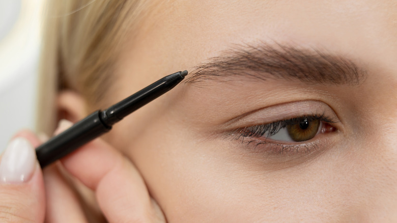 woman using eyebrow pencil