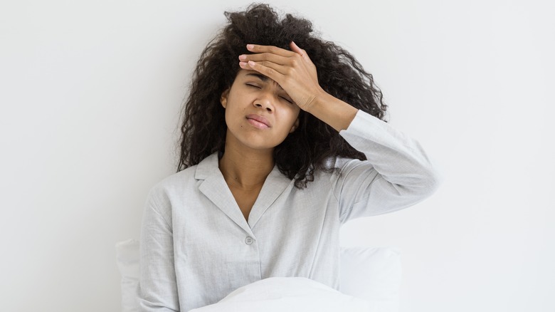 Woman waking up with headache, concept of hangover