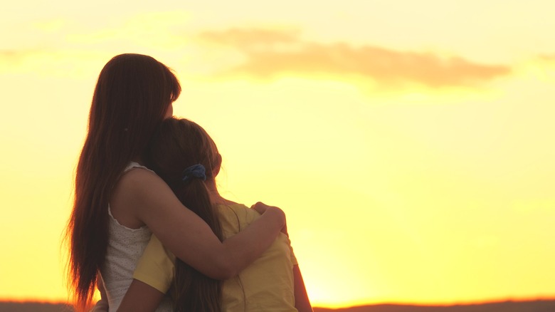 Mother hugging daughter