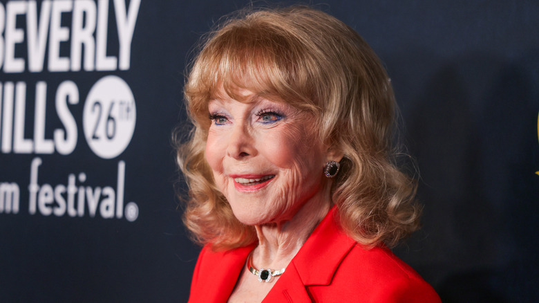 Barbara Eden smiles wearing a red blazer