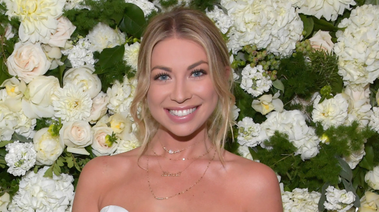 Stassi Schroeder smiling with floral backdrop