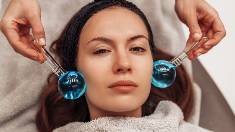 Woman receiving ice roller facial