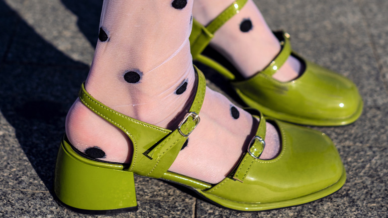 Close up of someone wearing green Mary Janes and polka dot tights