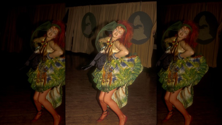 Cyndi Lauper wearing a detailed green dress and a green scarf headband and dancing at the Grammys.
