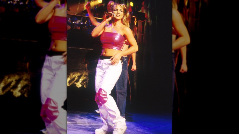 Britney Spears on stage in a hot pink tube top and white cargo pants.