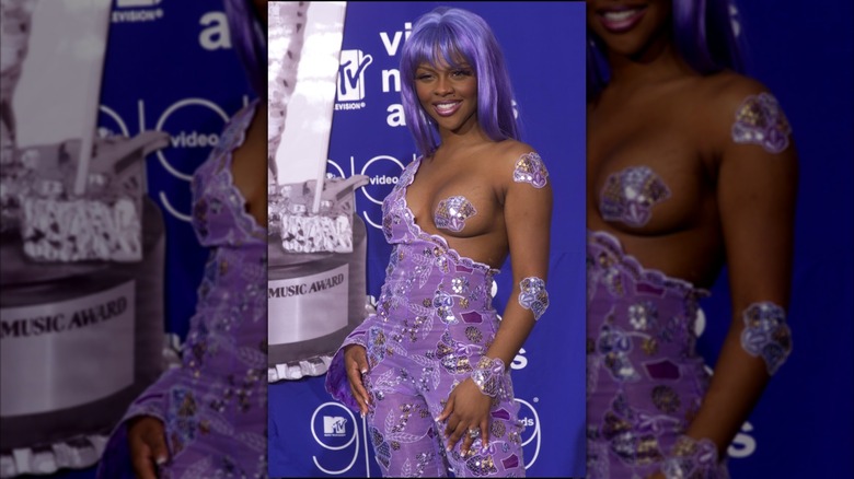 Lil Kim at the 1999 MTV VMAs with an embellished lavender jumpsuit and one breast sticking out covered by a purple pastie.