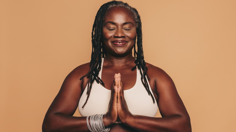 Woman meditating near yellow background