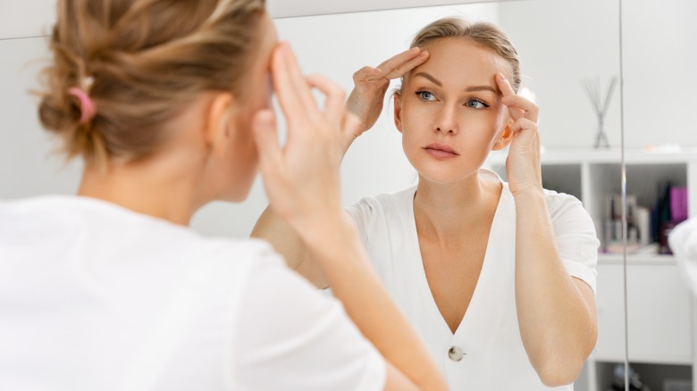 Woman looking at skin in mirror