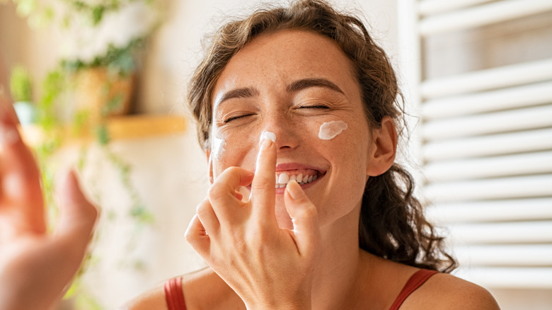 A woman putting on face cream 