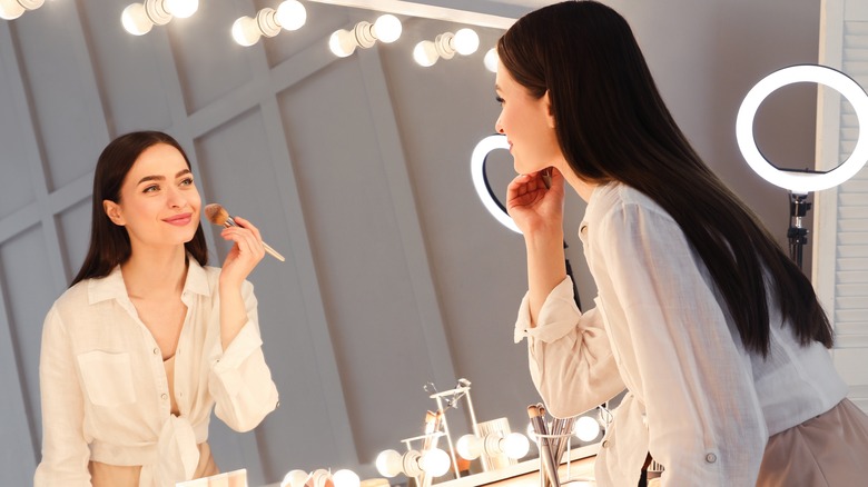 woman applying powder to face 