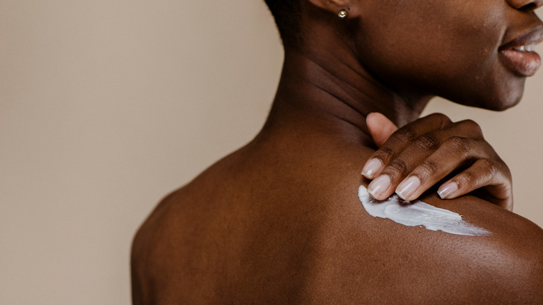 woman rubbing cream into her back