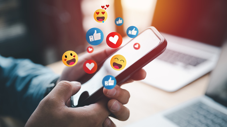 Person holding phone with emojis 