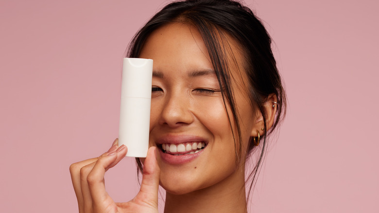 A woman holding a skincare bottle 