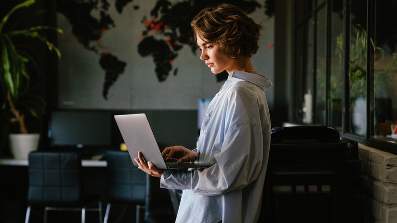 Woman standing, using laptop