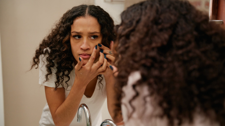 woman squeezing pimple