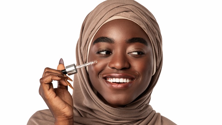 Woman applying a serum to her face