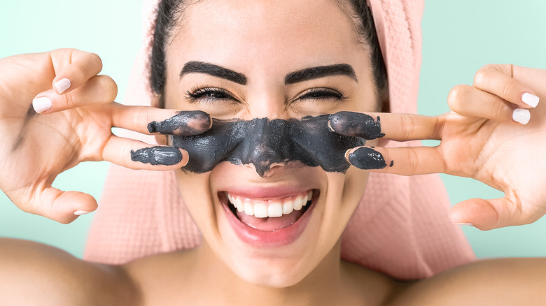 woman applying charcoal product on her face