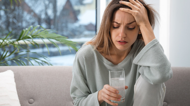 Woman with hangover drinking water