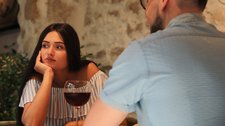 woman looking bored sitting opposite man