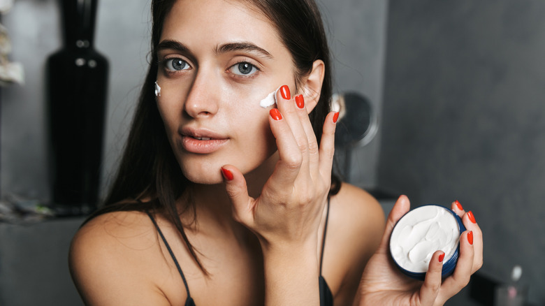 person putting on face cream