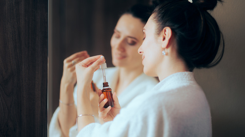 woman holding bottle of retinol near mirror