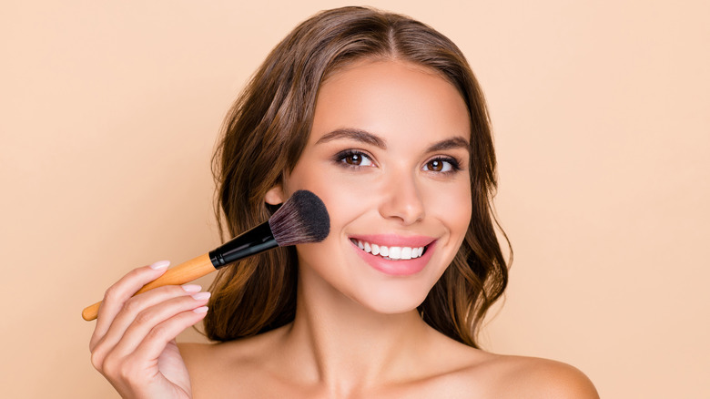 Woman smiling while applying highlighter