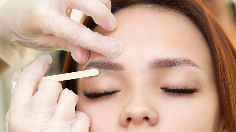 Model getting eyebrows waxed