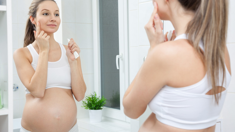 Pregnant woman applying skincare 