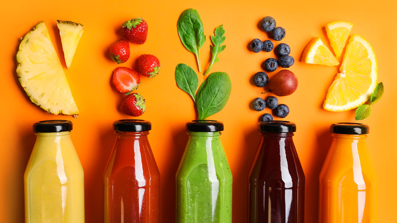 Bottles of fresh juices beneath assorted cut produce