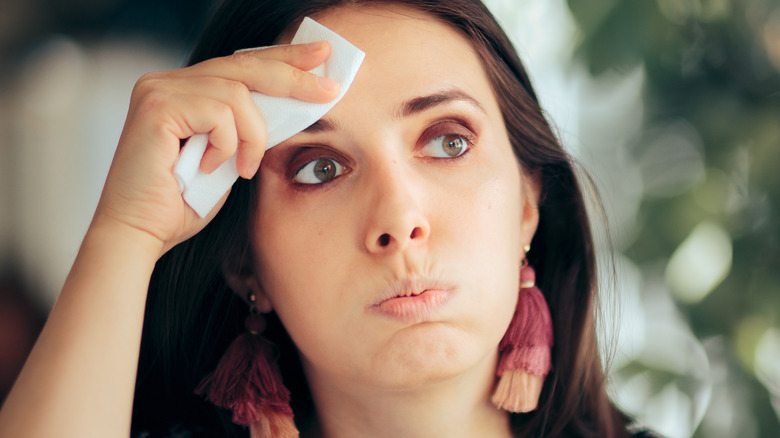 woman wiping sweat off her forehead with a tissue