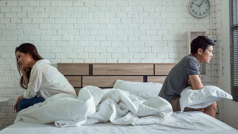 Distressed couple on opposite sides of bed