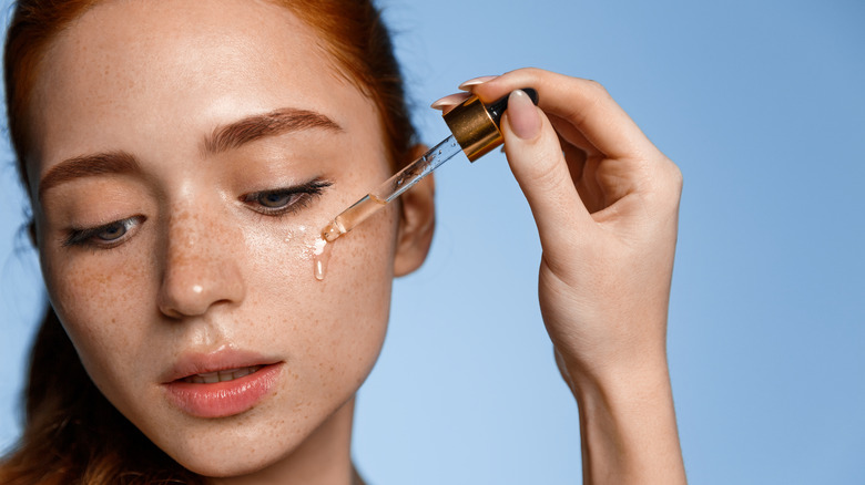 A woman applying face serum