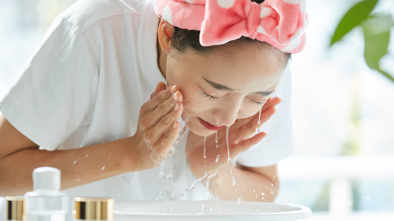 Woman washing face, smiling