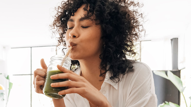 Black woman drinking green smoothie